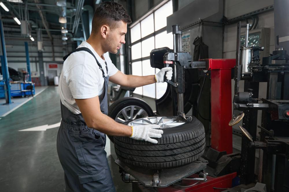 A mechanic using a tire changer machine to mount a tire onto a wheel in an auto repair shop, expertly handling the process of car tire replacement.