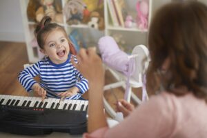 A boy wearing headphones stands in front of a microphone, singing or speaking, with a music stand and guitar in the background—perfect for those searching for singing classes for kids near me.